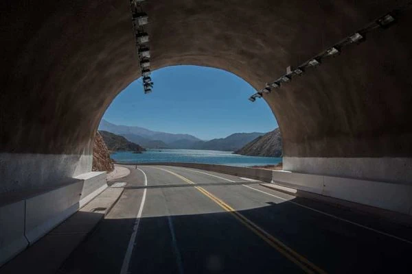 Túnel de carretera moderno con vista a montaña azul y lago