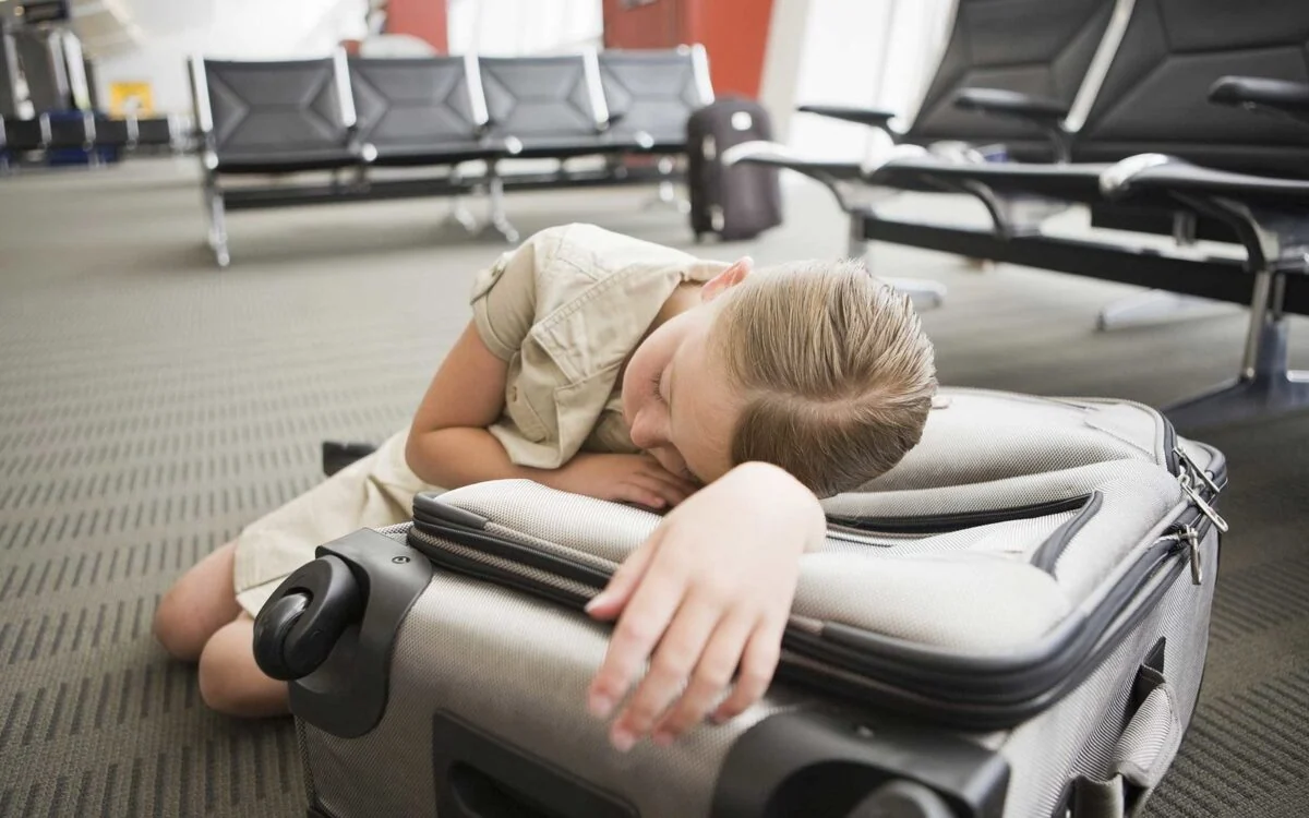 Pasajera descansa sobre equipaje en sala de espera de aeropuerto