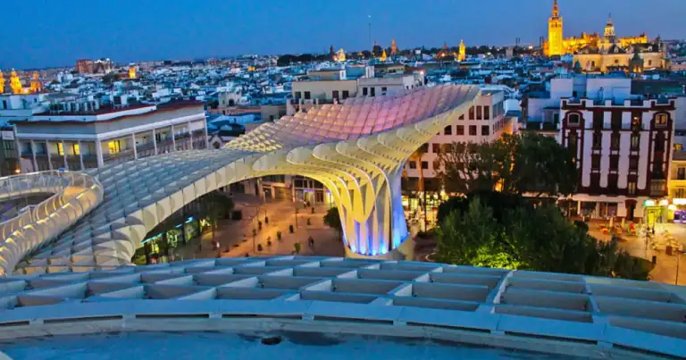 Estructura moderna ondulante iluminada al atardecer en ciudad