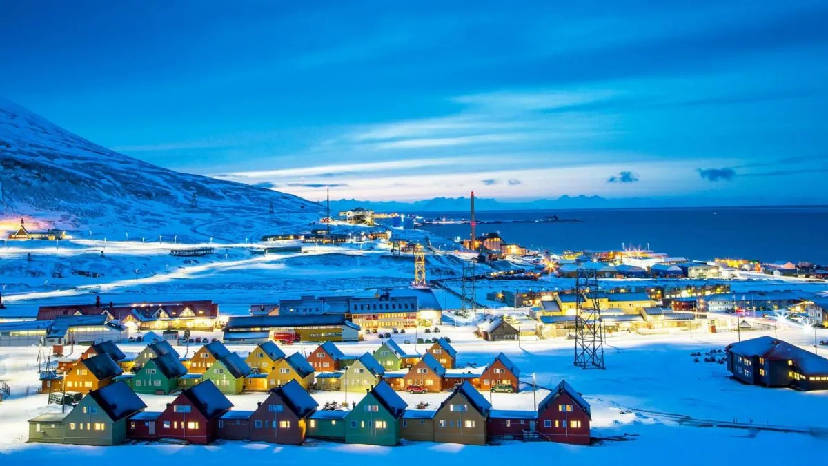 Pueblo alpino con casas cubiertas de nieve al atardecer bajo montaña nevada