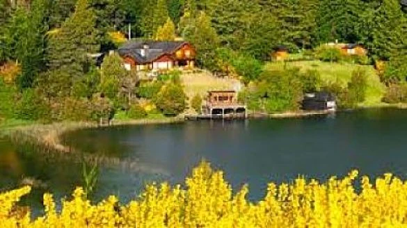Casa roja junto a lago boscoso rodeada de vegetación verde