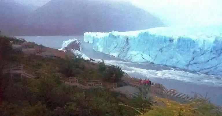 Glaciar de hielo azul con montañas al fondo en paisaje cordillerano