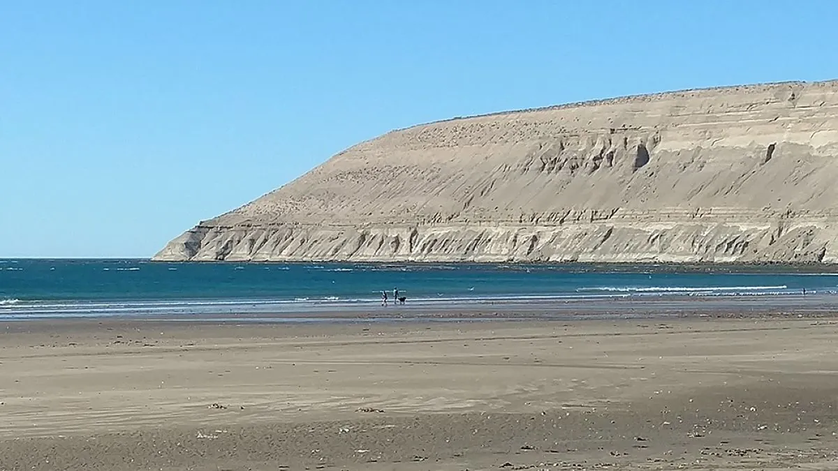 Playa con arena clara junto a acantilado alto de piedra color crema