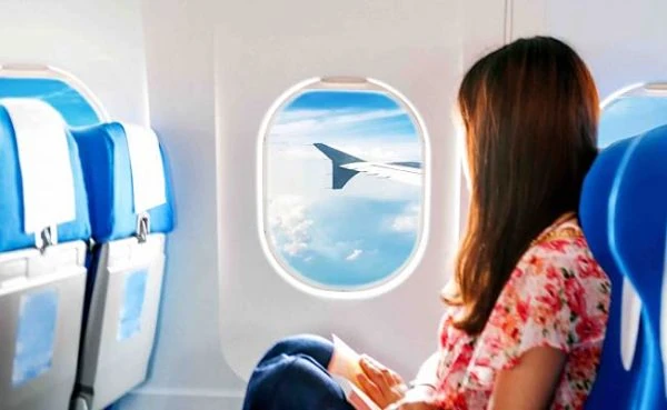 Pasajera mirando por ventanilla de avión con vista de ala en vuelo