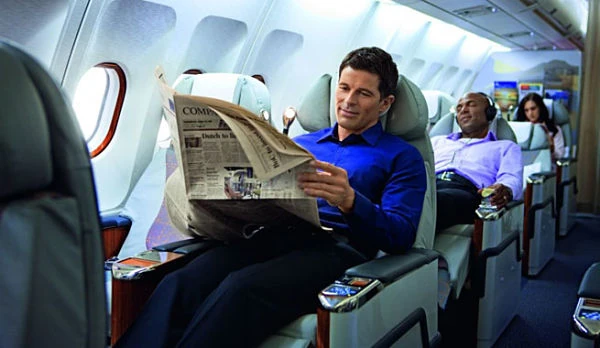 Hombre leyendo periódico en asiento del avión junto a ventanilla
