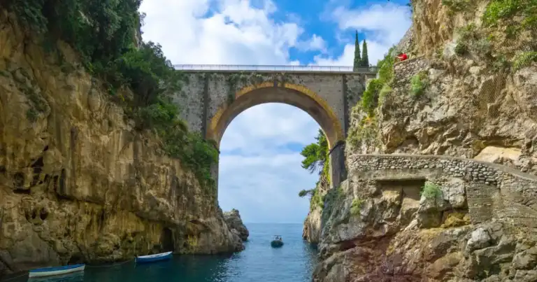 Arco natural de piedra enmarcando vista al mar con vegetación