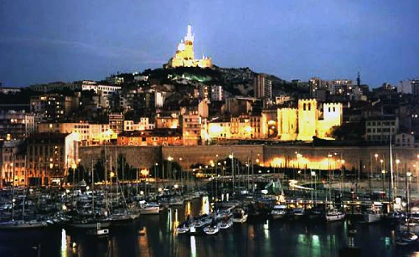 Puerto de Marsella al anochecer con basílica iluminada en la colina