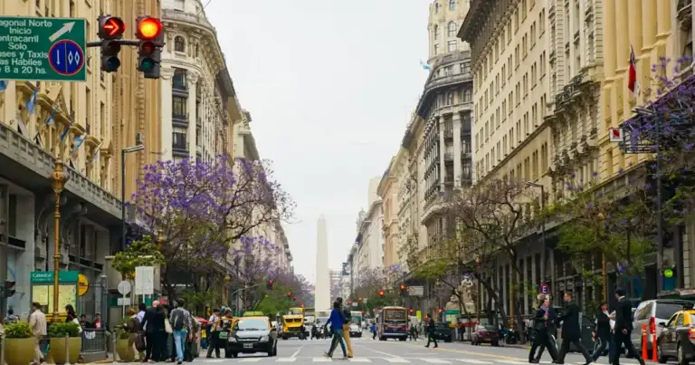 Avenida peatonal arbolada con locales comerciales y visitantes caminando