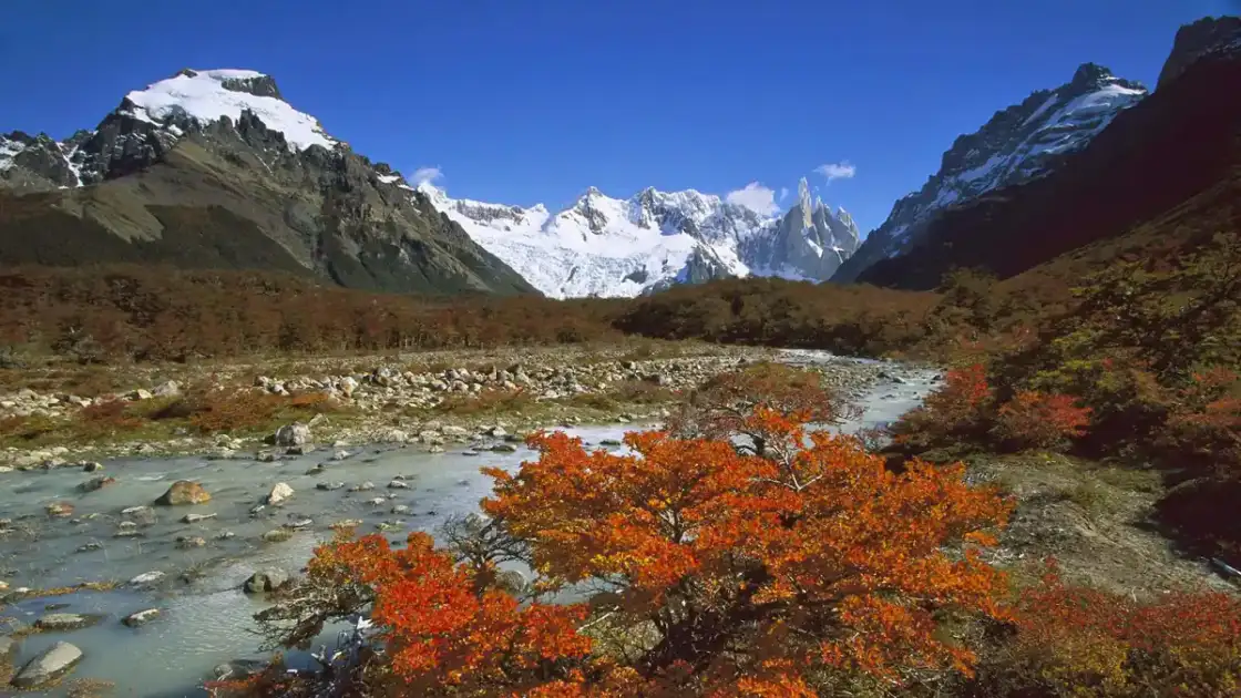 Valle de montañas nevadas con río turquesa fluyendo entre acantilados