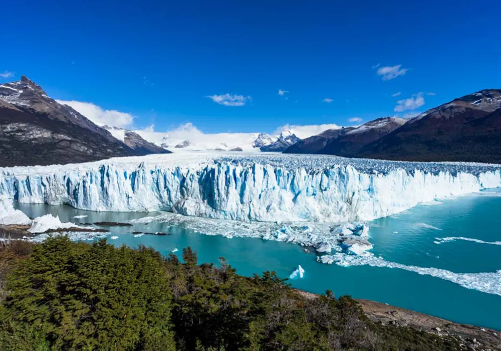 Glaciar Perito Moreno con formaciones de hielo azul, agua turquesa y montañas nevadas