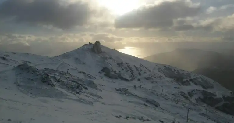 Montaña cubierta completamente de nieve bajo cielo nublado