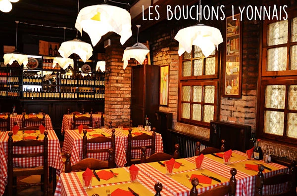 Interior rústico de restaurante con mesas de cuadros rojos, lámparas blancas y decoración de ladrillo