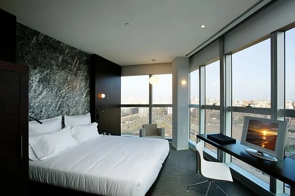 Dormitorio moderno con cama blanca y ventanales con vistas de la ciudad