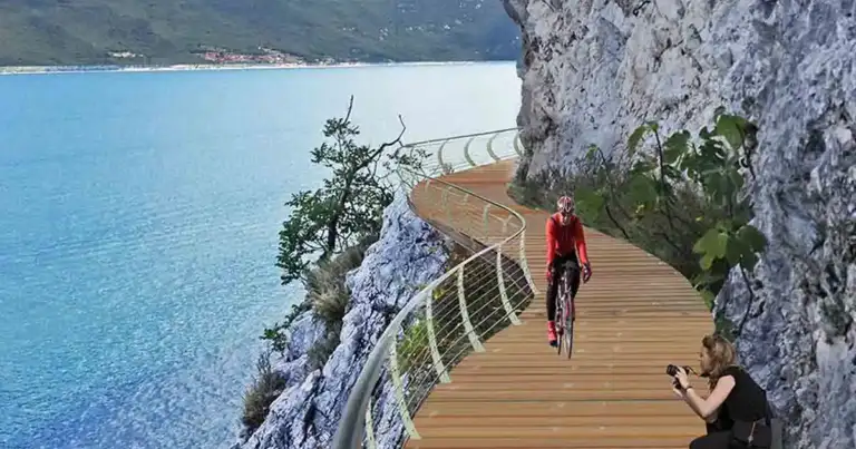 Ciclista en bicicleta en pasarela flotante sobre lago rodeado de acantilados