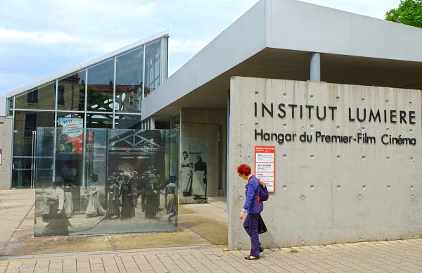 Entrada moderna del Instituto Lumière con paneles de vidrio y cartel