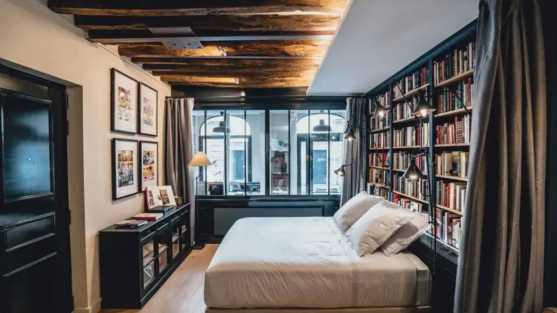 Dormitorio dentro de librería con estantes de libros y techo de vigas