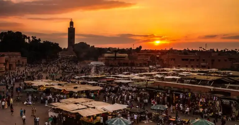 Plaza concurrida al atardecer con mezquita al fondo bajo cielo dorado