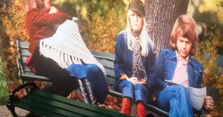 Mural fotográfico de tres personas sentadas en un banco de parque, en un otoño con hojas doradas