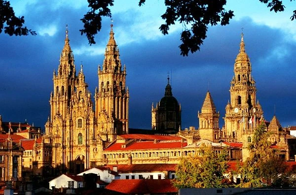Catedral con torres doradas iluminadas al atardecer bajo cielo nublado