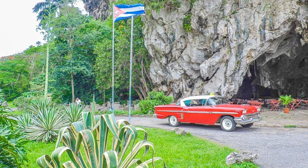 Auto vintage rojo de los años 50 frente a cueva rocosa