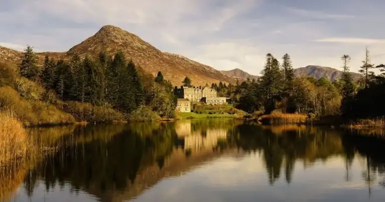 Castillo histórico reflejado en agua tranquila rodeado de árboles