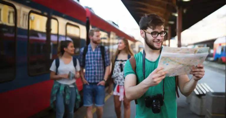 Joven con mapa en mano en andén de estación de tren
