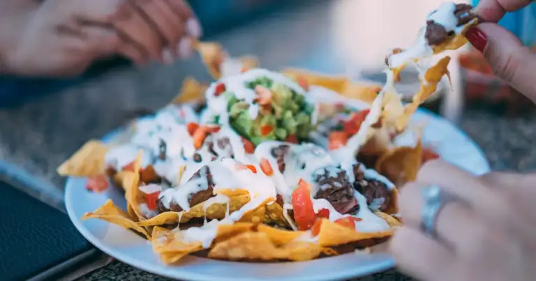 Personas compartiendo nachos con toppings y salsas en plato