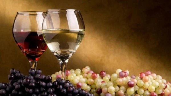 Copas de vino tinto y blanco con uvas verdes y moradas