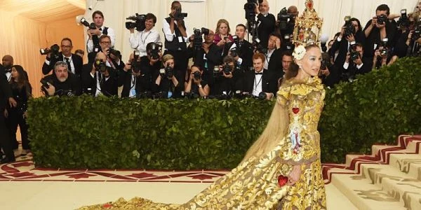 Persona con vestido largo dorado en evento de gala rodeada de invitados