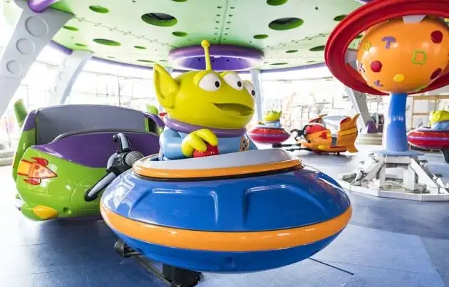 Nave alienígena amarilla y juguetes gigantes de Toy Story en área de parque temático