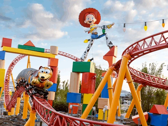 Parque temático con montaña rusa roja y estatuas de personajes en estructura colorida