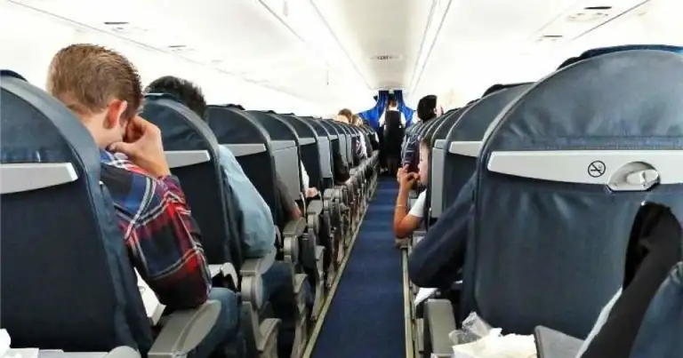 Interior de avión con pasajeros en asientos durante vuelo