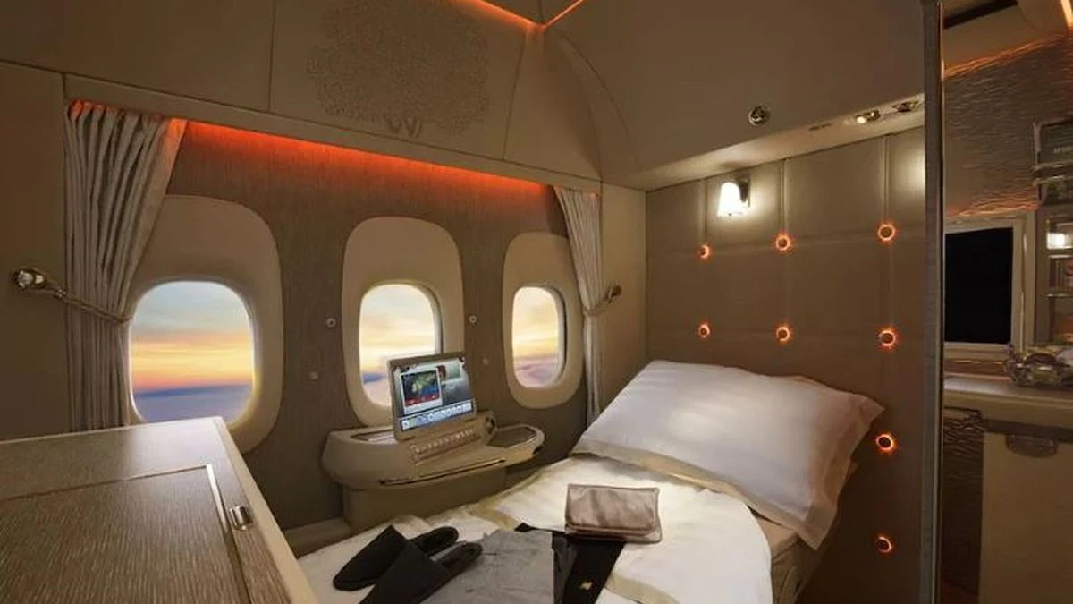 Suite de lujo en avión con cama, ventanilla y vista del atardecer