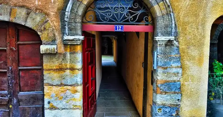 Puerta roja en pared de piedra antigua con rejilla de hierro decorativo