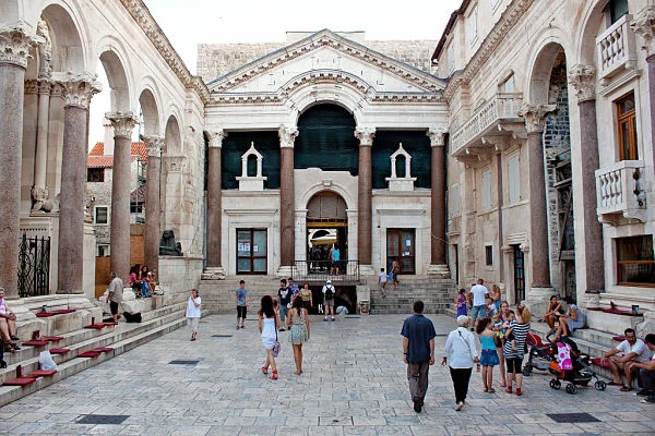 Pórtico arquitectónico histórico con arcos, turistas y luz solar