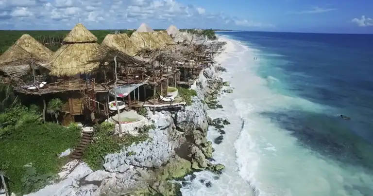 Cabañas de paja en acantilado con vista al mar turquesa