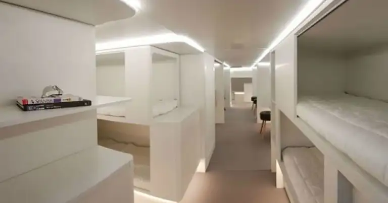 Interior moderno de bodega de avión con literas y iluminación LED blanca