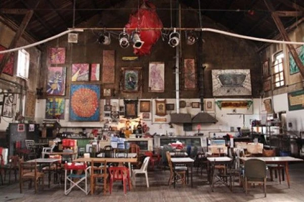 Interior de sala con techos altos, paredes con arte y mesas