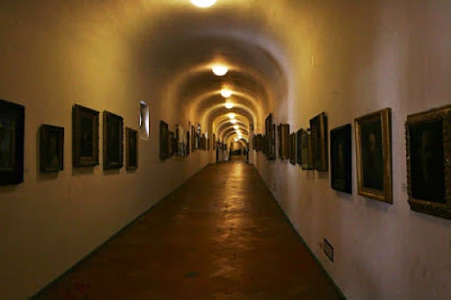 Interior del Corredor Vasariano con su colección de retratos históricos. Galería interna del Corredor Vasariano con retratos colgados en ambas paredes.