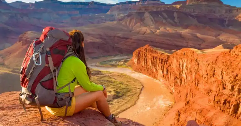 Mochilero en paisaje montañoso desértico con vista a cañón