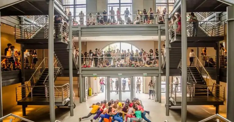 Bailarines en ropa de colores brillantes en espacio de teatro de múltiples niveles