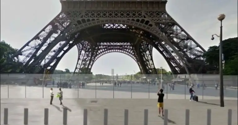Base de Torre Eiffel rodeada de vallas de vidrio con personas alrededor