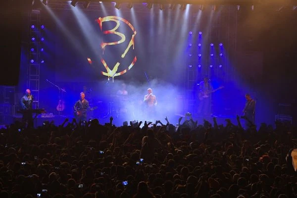 Multitud en concierto con escena iluminada y proyecciones