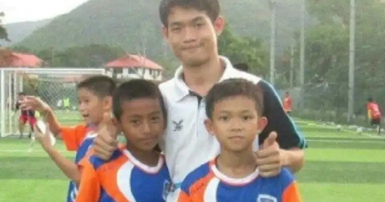 Entrenador y niños de un equipo de fútbol en Tailandia sonriendo para foto