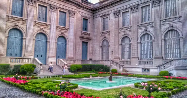Patio de mansión histórica con flores rosadas, fuente y arquitectura colonial