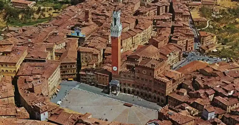 Vista aérea de ciudad medieval con tejados rojos y plaza central