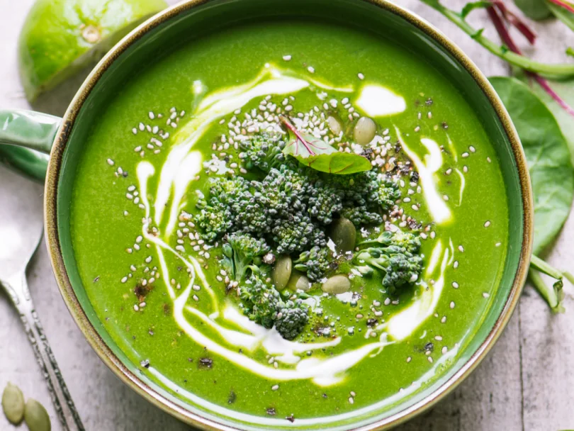Sopa de zapallo relleno: una receta saludable y reconfortante sopas bajas calorías Bowl de sopa verde decorada con semillas, brócoli y crema, servida sobre fondo rústico