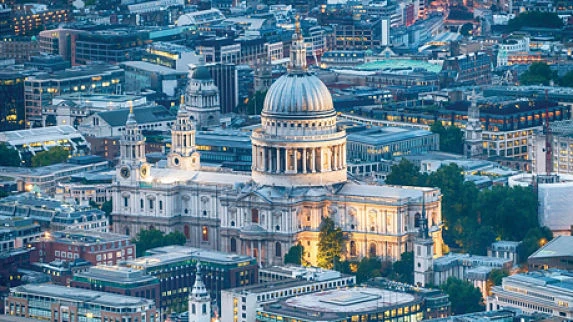 Catedral con cúpula blanca iluminada rodeada de edificios urbanos