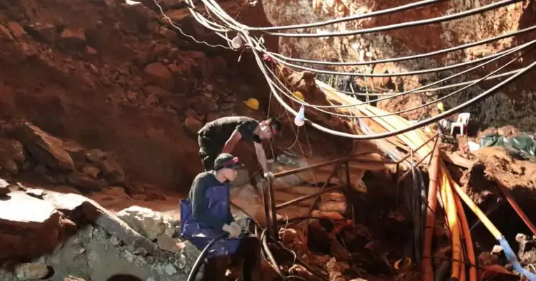 Persona con equipo de rescate en cueva rocosa roja con cuerdas