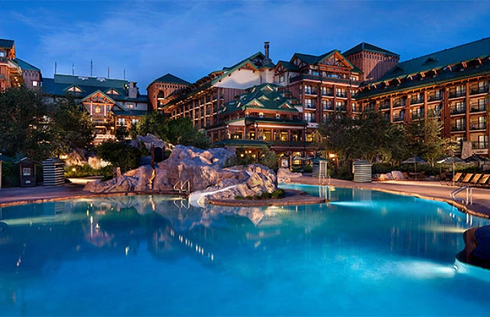 Piscina azul turquesa con arquitectura de resort hotelero y palmeras al anochecer